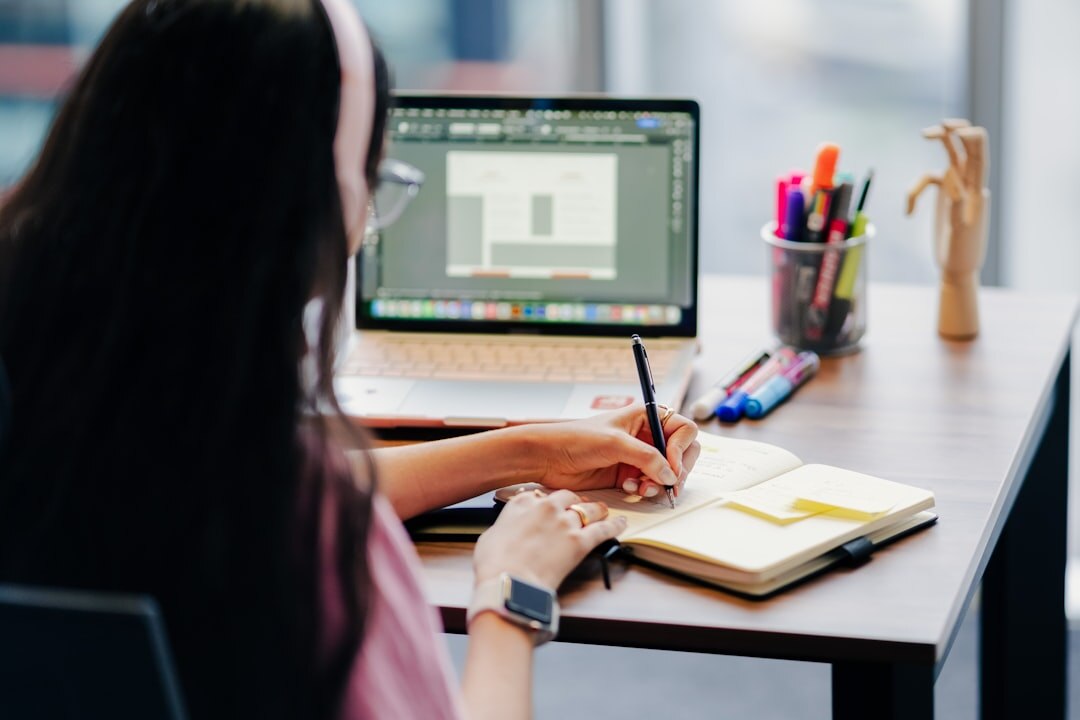 Person writing notes in a notebook at a desk